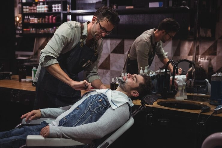 Barber giving a relaxing hot towel shave to a customer at a stylish barbershop in Bali