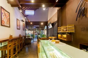 Narrow cafe interior with wooden bench seating leading to an outdoor courtyard