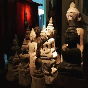 Collection of ancient wooden Buddha statues displayed in a dimly lit museum room