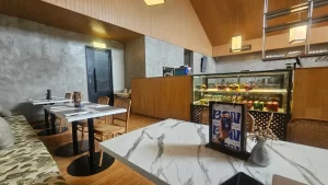 Modern cafe dining area with marble tables and a pastry display case