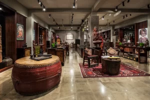Spacious art and antique gallery interior showcasing Asian artifacts, wooden furniture, and a large traditional drum