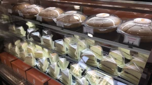 Bakery display case filled with packaged whole chiffon cakes and sliced cake wedges