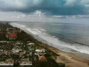 Aerial view of tropical beach resort with luxury villas, palm trees, and ocean waves along the coastline