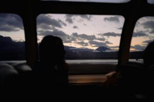 Silhouette of people inside vehicle enjoying mountain landscape view at sunset