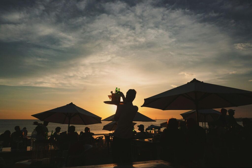 Waiter serving drinks at beach bar during beautiful sunset