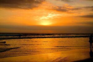 Golden sunset over the ocean with a person walking along the beach